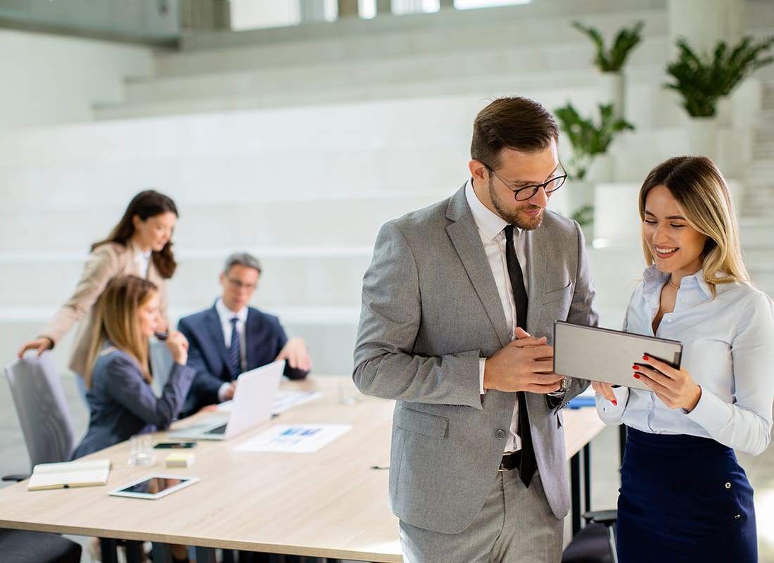 We Are Independent - Business Couple Looking at Financial Results on Digital Tablet in Front of Their Team at the Office