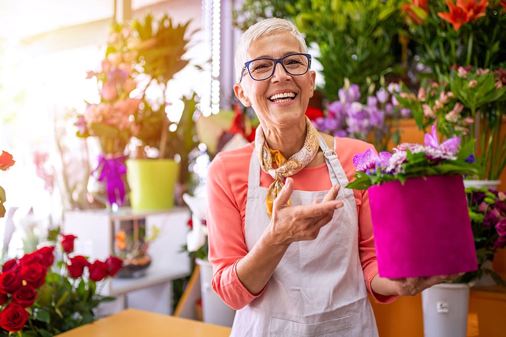 Insurance by Industry - Mature Smiling Florist Shop Owner Surrounded by Flowers
